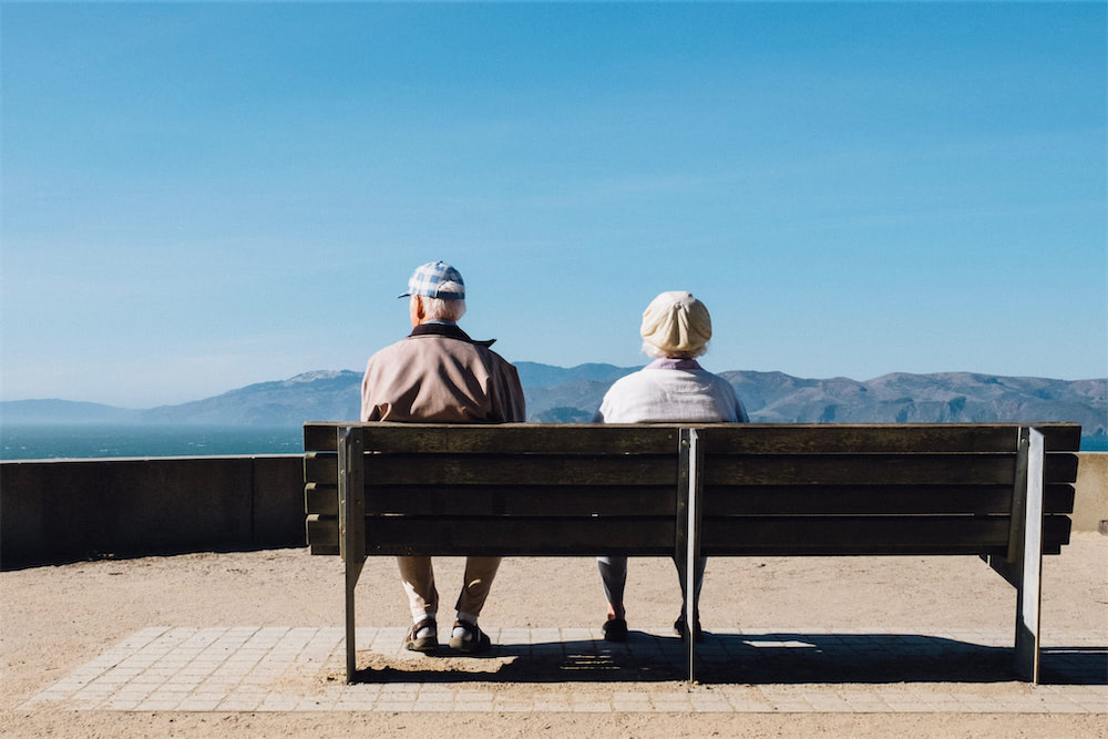 Ein altes Ehepaar sitzt auf einer Bank.