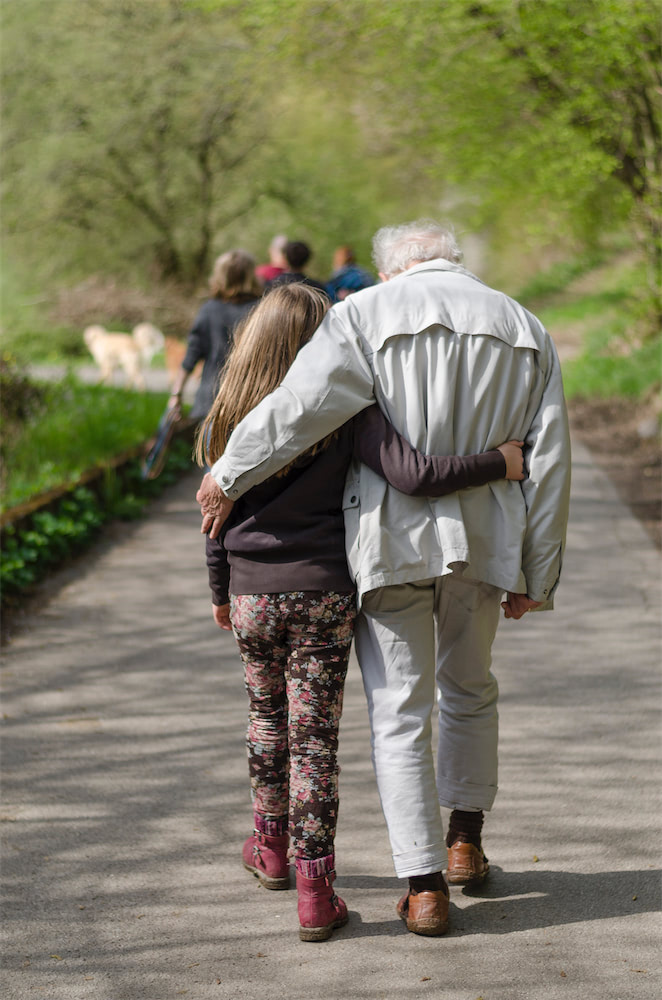 Ein pflegebedürftiger Herr geht mit seiner Enkelin spazieren.